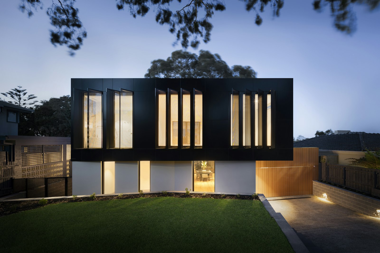 Contemporary home at dusk with warm interior light